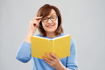 Image showing portrait of senior woman in glasses reading book