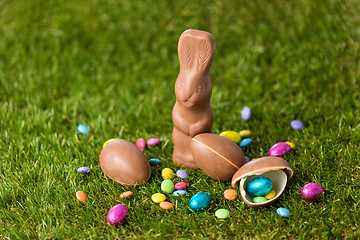 Image showing chocolate bunny, eggs and candy drops on grass