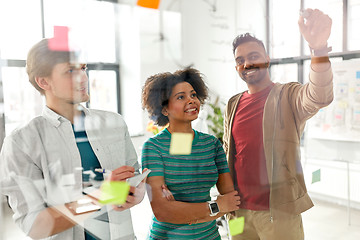 Image showing happy creative team at office glass board