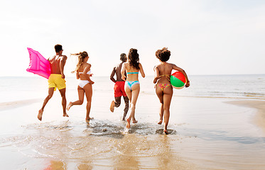 Image showing friends run with beach ball and swimming mattress