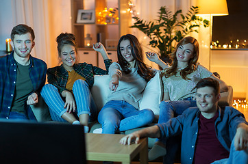 Image showing happy friends watching tv at home in evening