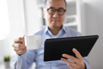 Image showing businessman with tablet pc drinks coffee at office