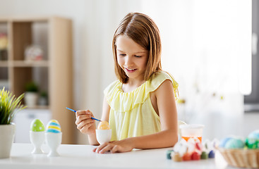 Image showing happy girl coloring easter eggs at home