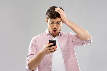 Image showing embarrassed young man looking at smartphone
