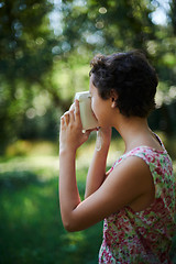 Image showing Active girl taking photo on instant camera in sunny forest