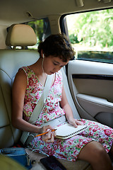 Image showing Thoughtful girl drawing in sketchbook in back seat of car