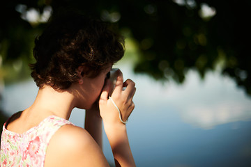 Image showing Active girl taking photo on instant camera in sunny forest