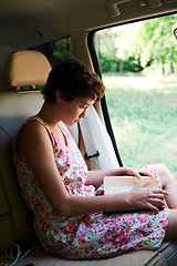 Image showing Enthusiastic girl reading book in car in trip