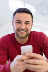 Image showing young man using a mobile phone  at home