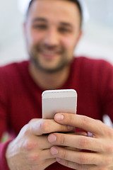 Image showing young man using a mobile phone  at home