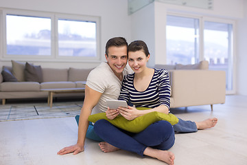 Image showing Young Couple using digital tablet on the floor