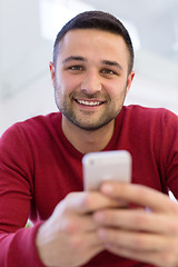 Image showing young man using a mobile phone  at home