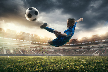 Image showing Young boy with soccer ball doing flying kick at stadium