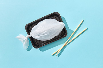 Image showing Plastic bag in a shape of fish on a plastic plate with chopsticks.