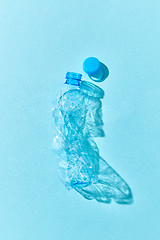 Image showing Empty used plastic bottle on a blue background with shadows.