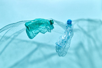 Image showing Plastic bottles in the blue ocean waves from plastic foil shadows.