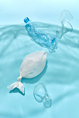 Image showing Ocean waves from shadows of plastic foil with floating bottle, fish and cups.