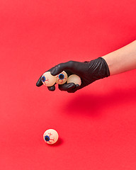 Image showing Woman hand in black glove with human eyeballs.