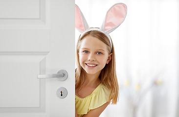 Image showing happy girl with easter bunny ears peeking out door