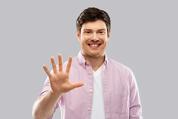 Image showing young man showing five fingers over grey