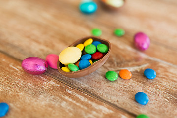 Image showing chocolate egg and candy drops on wooden table