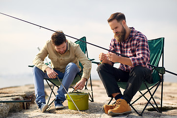 Image showing friends adjusting fishing rods with bait on pier