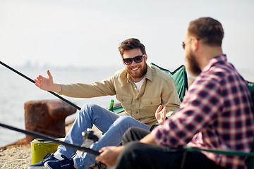 Image showing happy male friends with rods talking about fishing