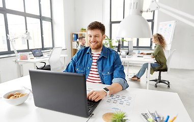 Image showing smiling creative man with laptop working at office