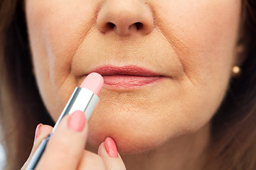 Image showing close up of senior woman applying lipstick