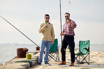 Image showing happy friends with fishing rods and beer on pier