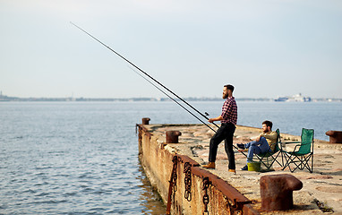 Image showing happy friends with fishing rods on pier