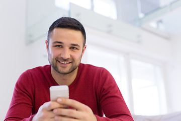 Image showing young man using a mobile phone  at home