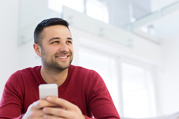 Image showing young man using a mobile phone  at home