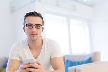 Image showing young man using a mobile phone  at home