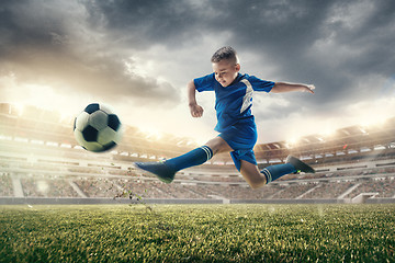 Image showing Young boy with soccer ball doing flying kick at stadium