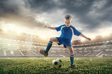 Image showing Young boy with soccer ball doing flying kick at stadium