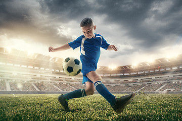 Image showing Young boy with soccer ball doing flying kick at stadium