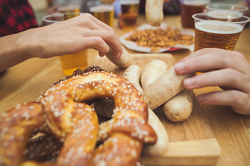 Image showing Boiled white sausages, served with beer and pretzels. Perfect for Octoberfest. Natural wooden background.