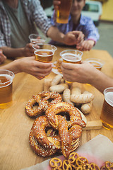 Image showing Boiled white sausages, served with beer and pretzels. Perfect for Octoberfest. Natural wooden background.