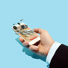 Image showing Conceptual image of Businessman holding screen of mobile phone with coins as dollar sign