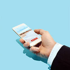 Image showing Hand holding smartphone with hotel booking application on the beach and blue sky