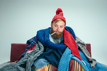 Image showing Bearded Man with Flue Sitting on Sofa at Home. Healthcare Concepts.