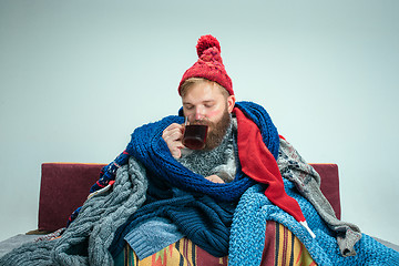 Image showing Bearded Man with Flue Sitting on Sofa at Home. Healthcare Concepts.