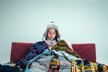 Image showing The young woman with Flue Sitting on Sofa at Home. Healthcare Concepts.