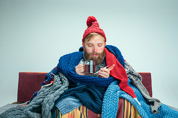 Image showing Bearded Man with Flue Sitting on Sofa at Home. Healthcare Concepts.