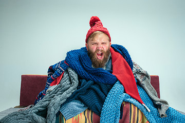 Image showing Bearded Man with Flue Sitting on Sofa at Home. Healthcare Concepts.