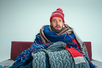 Image showing Bearded Man with Flue Sitting on Sofa at Home. Healthcare Concepts.