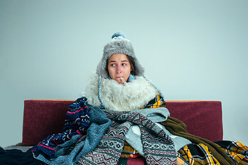 Image showing The young woman with Flue Sitting on Sofa at Home. Healthcare Co