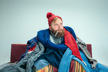 Image showing Bearded Man with Flue Sitting on Sofa at Home. Healthcare Concepts.