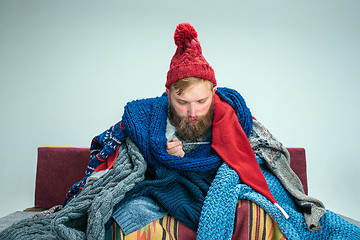 Image showing Bearded Man with Flue Sitting on Sofa at Home. Healthcare Concepts.